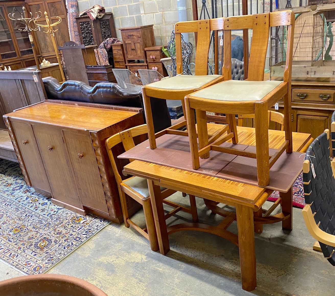 An early 20th century oak and zebra wood dining suite by Ebenezer Gomme, comprising draw leaf table, four chairs and sideboard